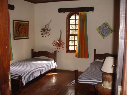 2 Betten in einem Zimmer mit Fenster in der Unterkunft Casa das dálias in Monte Verde