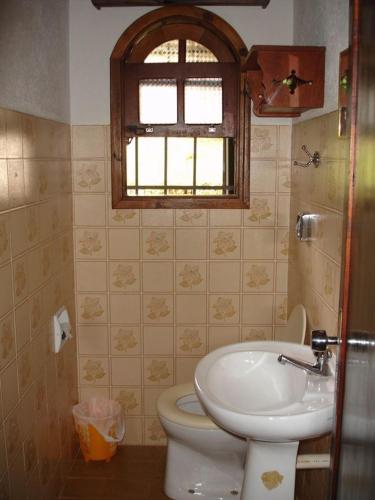 a bathroom with a toilet and a sink and a window at Casa das dálias in Monte Verde