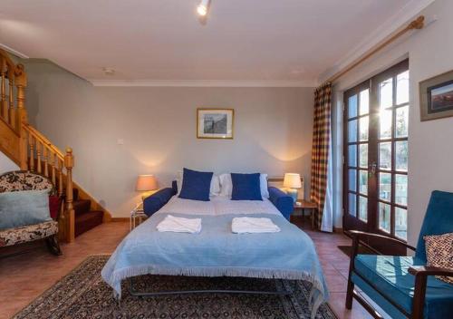 - une chambre avec un lit bleu et un canapé dans l'établissement The Old Mill Cottage - 10 Mins to St Andrews, à St Andrews
