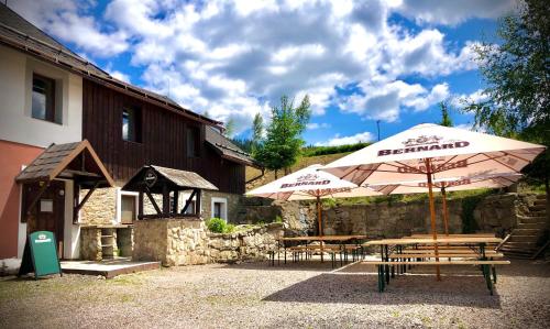 two tables and umbrellas in front of a building at Penzion Dolní Morava in Dolní Morava