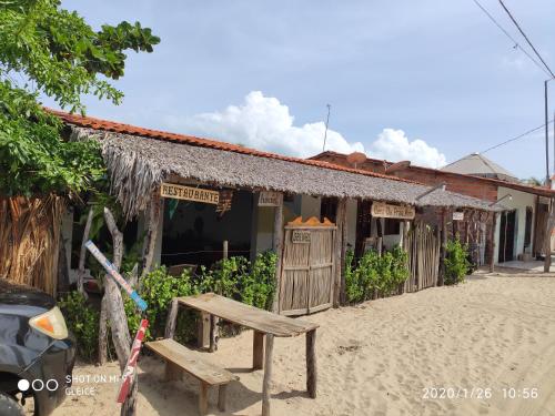 ein Gebäude am Strand mit einer Bank davor in der Unterkunft Casa da Praia.Atins in Atins