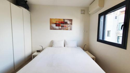 - un lit blanc dans une chambre avec fenêtre dans l'établissement BnB Israel Apartments - Shalom Alehem Joie, à Tel Aviv