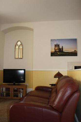 a living room with a leather couch and a flat screen tv at No2 Abbey View Apartment in Whitby