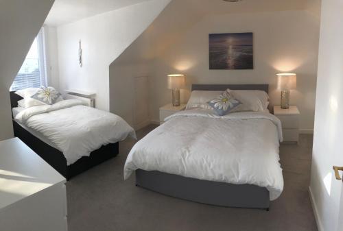 a white bedroom with two beds and a staircase at Arran Ferry Apartment in Ardrossan