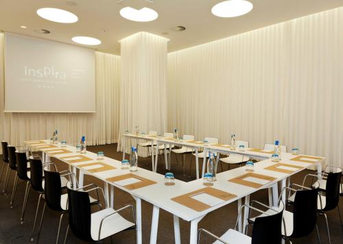 a conference room with long tables and chairs and a screen at Inspira Liberdade Boutique Hotel in Lisbon