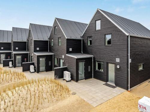 uma fila de casas com revestimento preto em 8 person holiday home in Bl vand em Blåvand