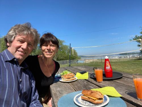 Een man en een vrouw aan een tafel met een broodje bij Les Cottages d'Orient Premium in Mesnil-Saint-Père