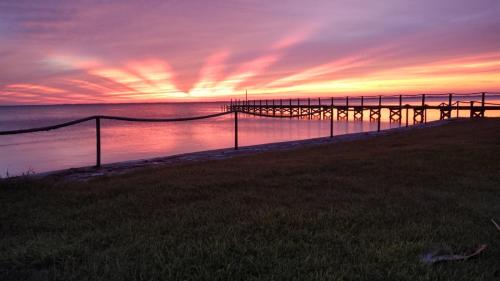 a pier on the water with a sunset at Nasa waterfront Dolphin Suite in Titusville