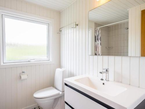 a bathroom with a sink and a toilet and a window at Holiday home Hvide Sande XCVI in Havrvig