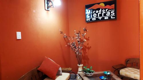 a living room with orange walls and a couch at Hotel Mirador de las Sierras in Villa Carlos Paz