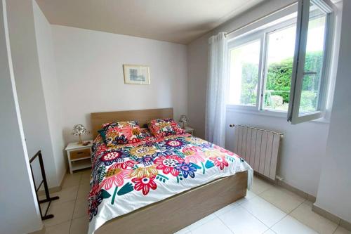 una camera da letto con un letto con copriletto floreale e una finestra di Villa au calme 500 m plages et port santa lucia a Saint-Raphaël