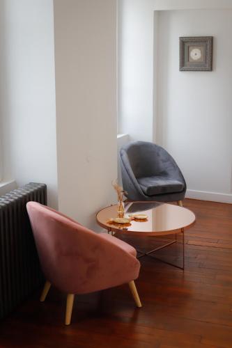 a living room with a pink chair and a table at Le Moulin Bleu in Saint Cyr-sous-Dourdan