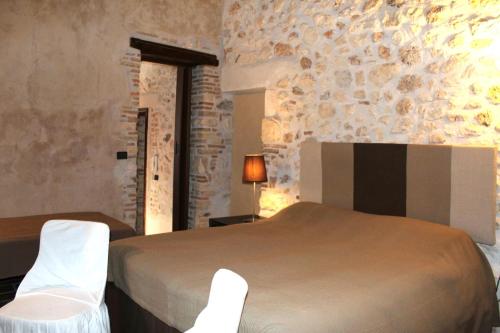 a bedroom with a bed and two white chairs at Apartments Parco d'Abruzzo in Bisegna