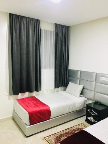 um quarto com uma cama com um cobertor vermelho em Hotel Soukina em Dakhla