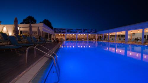 - une piscine de nuit avec des chaises et des tables dans l'établissement Hotel Pantelidis, à Ptolemaïda