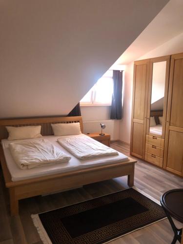Schlafzimmer mit einem großen Bett mit einem Kopfteil aus Holz in der Unterkunft Hotel Restaurant Artemis in Weisenheim am Berg