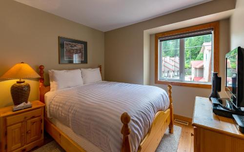 a bedroom with a bed and a television and a window at Stone Creek by StayIn in Fernie