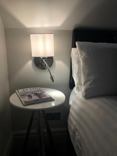 a table with a lamp and a book on it next to a bed at Ashbourne House in York