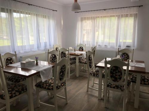 a dining room with tables and chairs and windows at Pensiunea Maria in Colibiţa
