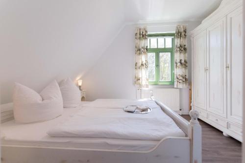a white bed in a room with a window at Ferienhaussiedlung Strandperlen Sanddornhof 3c (Typ II) in Wustrow