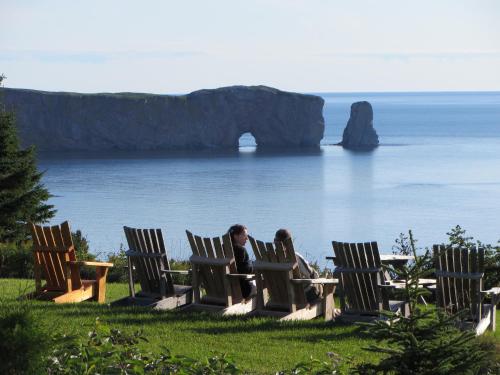 two people sitting in chairs looking at the ocean at Chalets Nature Océan in Perce
