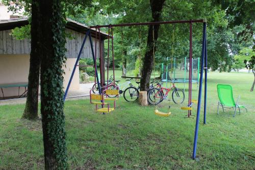 a swing set in a park with two bikes at Maison de Vacances MACOU 2 in Capdrot
