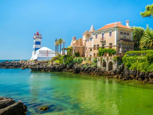 a house and a lighthouse next to a body of water at Villa Maça Guest House in Sintra