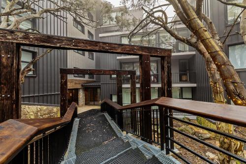 a wooden stairway with a tree in front of a building at Chalet Apartments - Mt Buller Apartment Rentals in Mount Buller
