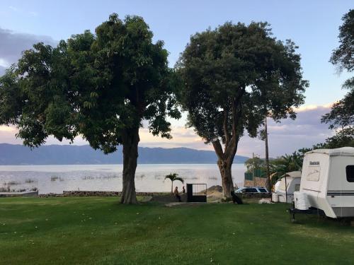 an rv and two trees next to the water at Casa Bravía - Hotel·RV in San Luis Soyatlán