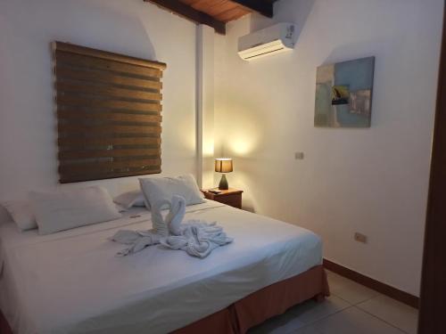 a bedroom with a bed with white sheets and a window at Galapagos Dreams in Puerto Ayora