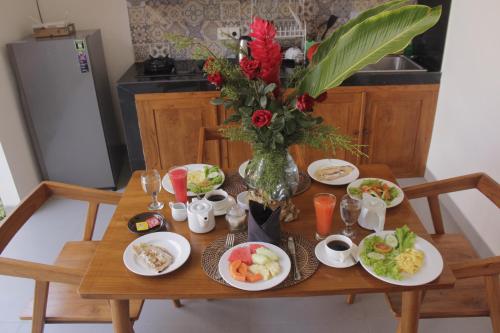 a table with plates of food and a vase of flowers at Ratna Villa in Ubud
