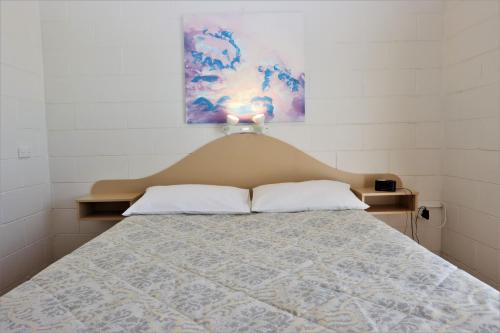 Lake Edge Apartments في Burrill Lake: غرفة نوم مع سرير مع لوحة للرأس