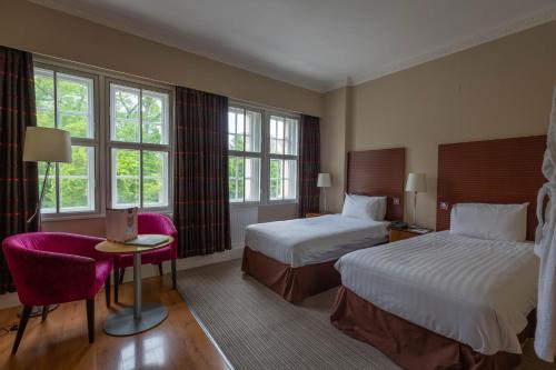 a hotel room with two beds and a table and chairs at The Angel Hotel in Cardiff