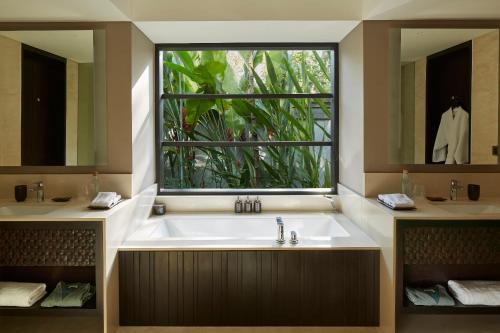 a bathroom with a large bath tub with a window at Nirjhara in Tabanan