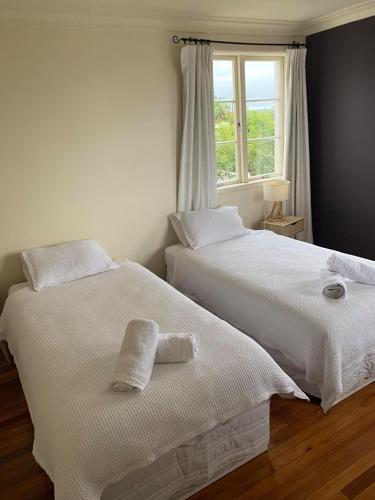 two white beds in a room with a window at Kiwi Heritage Homestay in Auckland