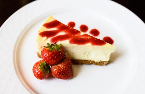 a piece of cheesecake with strawberries on a white plate at The Angel Hotel in Cardiff