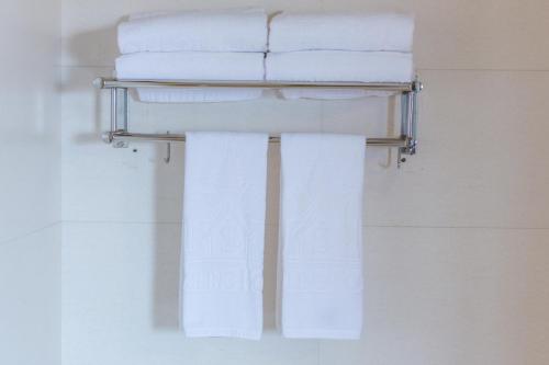 a towel rack with white towels on it in a bathroom at Smiling Hotel in Siem Reap