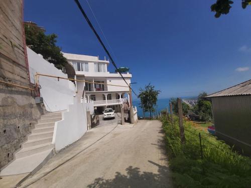 a white building with a car parked on a street at Goga Guest House in Kvariati