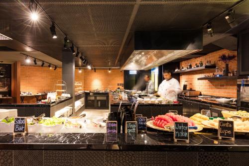 a kitchen with a chef preparing food in a restaurant at La Vela Khao Lak - SHA Extra Plus in Khao Lak