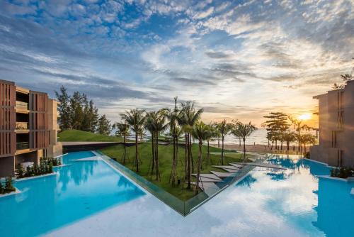 a large swimming pool with palm trees in a resort at La Vela Khao Lak - SHA Extra Plus in Khao Lak