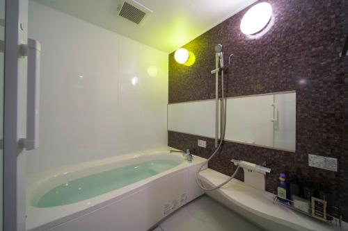 a bathroom with a bath tub and a mirror at HOTEL LASCALA in Wakayama