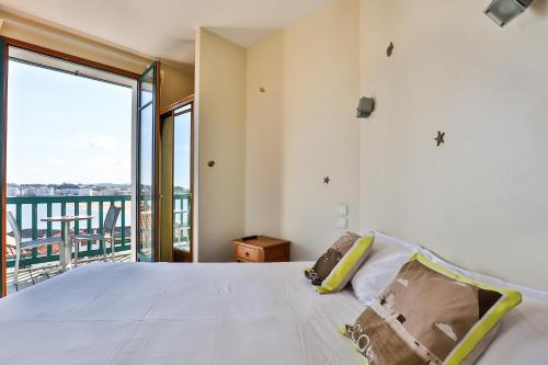 a bedroom with a large bed and a balcony at Hotel Agur Deneri in Ciboure