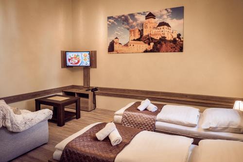 a hotel room with two beds and a tv at Hotel Kaskada in Poprad