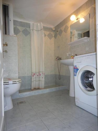 a bathroom with a toilet and a washing machine at Apergis Rooms in Ermoupoli