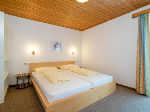Schlafzimmer mit einem Bett mit weißer Bettwäsche und einer Holzdecke in der Unterkunft Appartements Maurer in Flachau