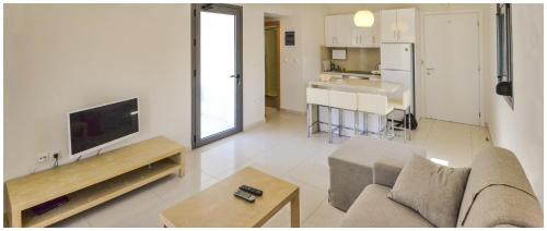 a living room with a couch and a tv and a kitchen at Potideon Bay Luxury Apartments in Karpathos