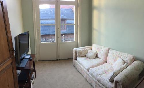 a living room with a couch and a television at Villa Theresa à 25 min de PAIRI DAIZA in Soignies