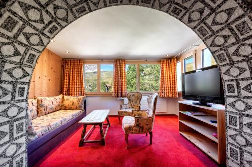 a living room with a couch and a tv at Hotel Gspan in Arosa