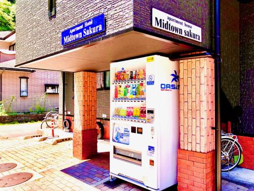 a white refrigerator in front of a building at Midtown Sakura Apartment House 201 予約者だけの空間 A space just for you in Katsuura