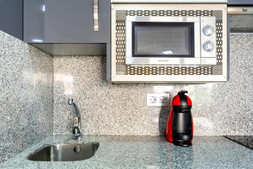 a kitchen with a fire extinguisher on a counter next to a microwave at Apartamento primera linea playa Algarrobo Costa in Algarrobo-Costa